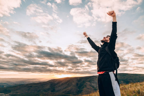 istock Young man cheering on top of mountain 830053156