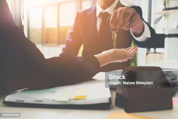 Estate Agent Giving House Keys To Man And Sign Agreement In Office Stock Photo - Download Image Now