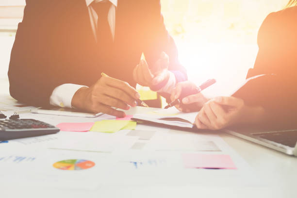 istock Close-up of business man and partner hands pointing at turnover graph while discussing it using laptop and calculator 830071518