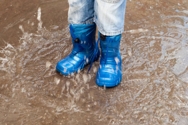 istock child with rain boots jumps into a puddle 830079876