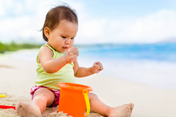 istock Two year old toddler playing with her toys on the beach 830132608