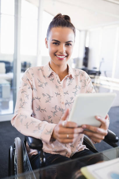 retrato de empresaria sonriente con tableta digital mientras está sentado en silla de ruedas - physical impairment smiling front view looking at camera fotografías e imágenes de stock