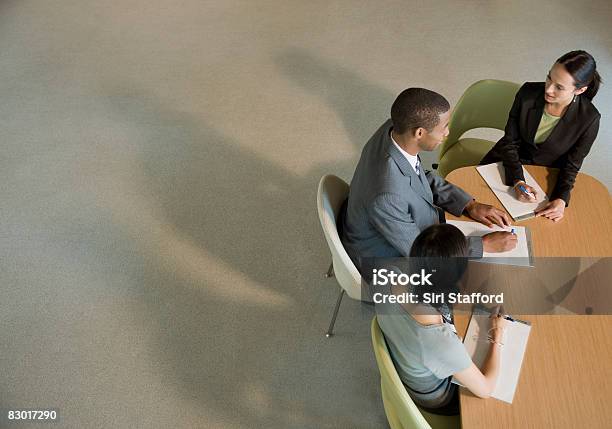 Foto de Trabalhadores De Escritório Na Mesa De Reunião e mais fotos de stock de Reunião de negócios - Reunião de negócios, Reunião, Três Pessoas