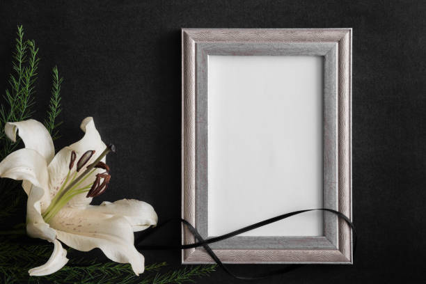 istock White blank condolence card with frame and lily flowers on the dark background. Empty place for a text or photo. 830190500