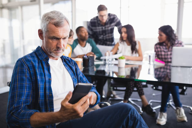 istock Serious businessman using mobile phone with team working in background 830195812