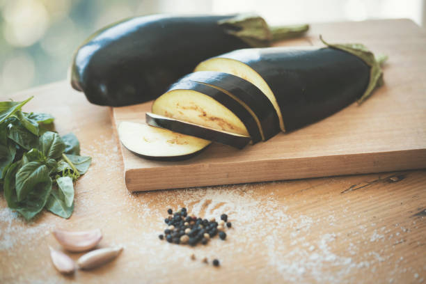 Close up of chopped eggplant on cutting board and mess on kitchen table, peppercorn and salt spilling.