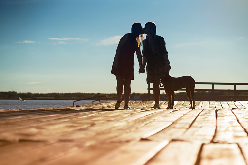 Lesbian couple with dog on wooden dock