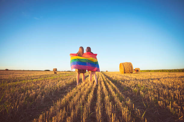 Lesbian couple with LGBT flag on a cropped field