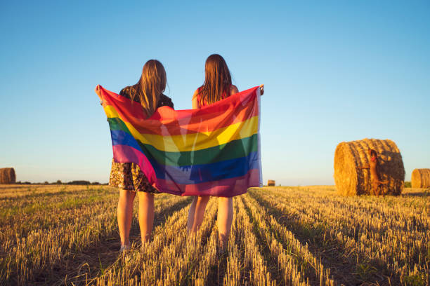 istock Lesbian couple with LGBT flag on a cropped field 830239508