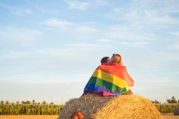 istock Lesbian couple with LGBT flag on a cropped field 830240182