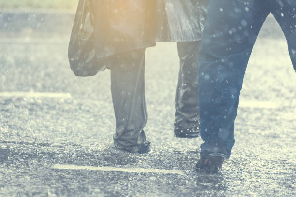istock People running away through puddle at street during heavy rain. 830242416