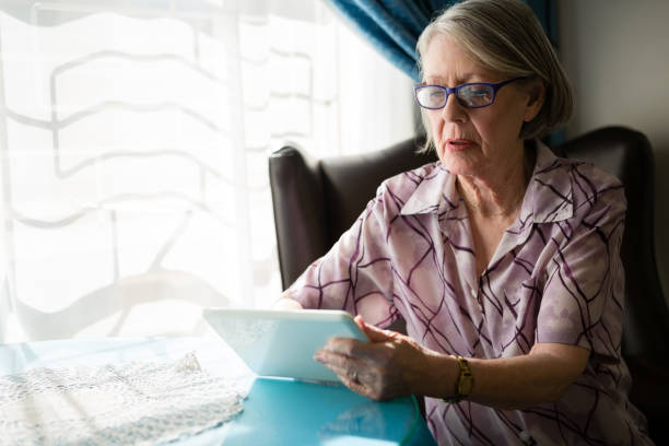 istock Senior woman using digital tablet while sitting in nursing home 830245662
