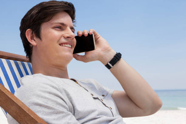 istock Smiling man talking on mobile phone at beach 830246856