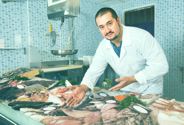 istock Man in white cover-slut showing fish on counter 830291288