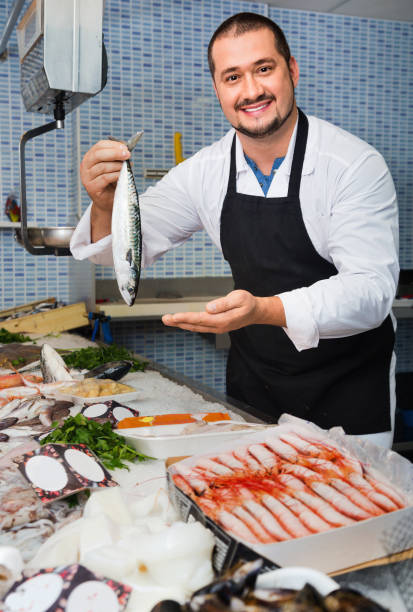 istock Seller behind scales and fish counter showing fish 830291474