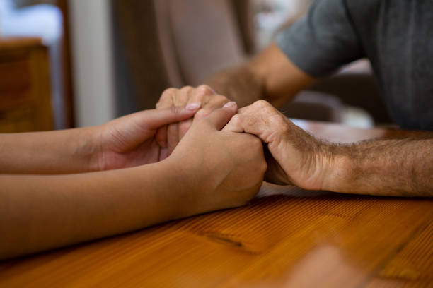 istock Female doctor and senior man holding hands at table 830305824
