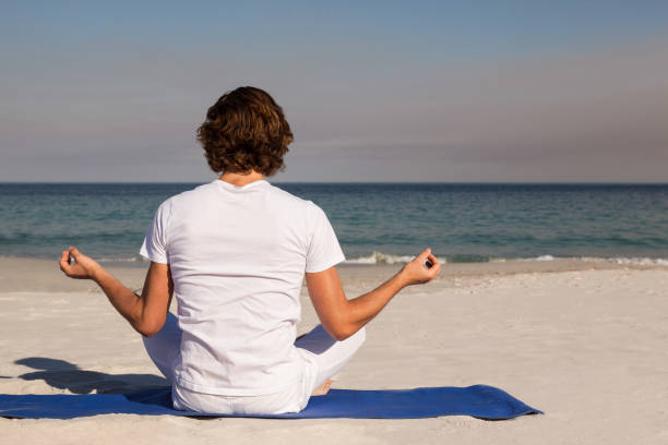 istock Man performing yoga at beach 830312892