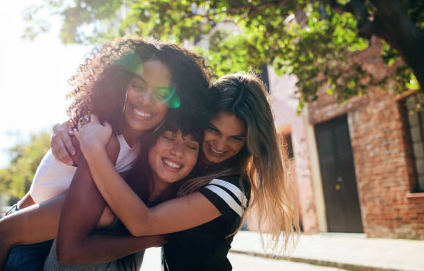 Group of female friends enjoying outdoors on city street Three happy young women embracing each other on city street and smiling. Group of friends enjoying outdoors on city street. street friends stock pictures, royalty-free photos & images
