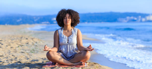 istock African woman sitting on sand and meditating 830353028