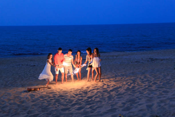 istock Friends celebrating with flaming torches on beach 830353236
