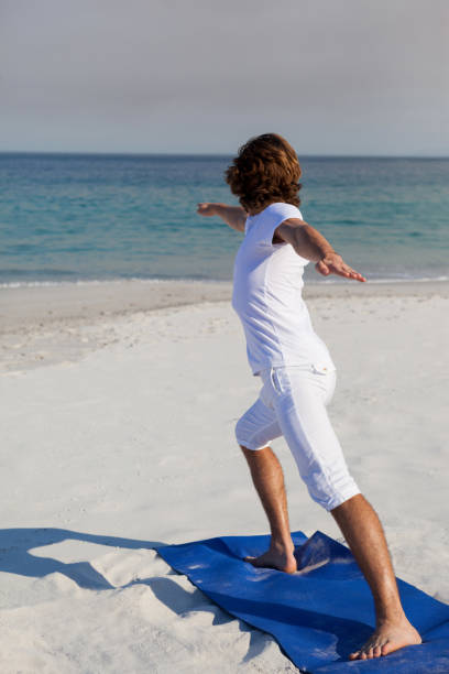 istock Man performing yoga at beach 830356814