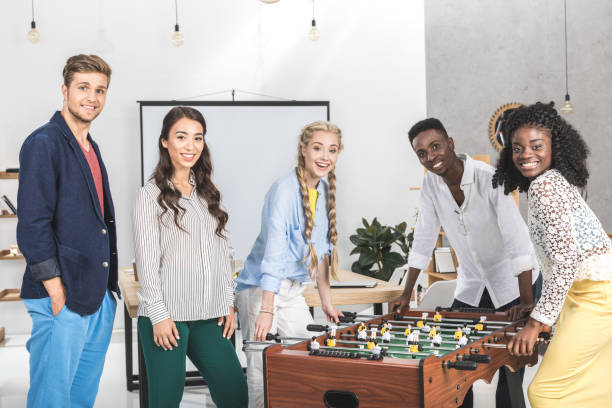 istock smiling business people looking at camera while playing table football 830366766