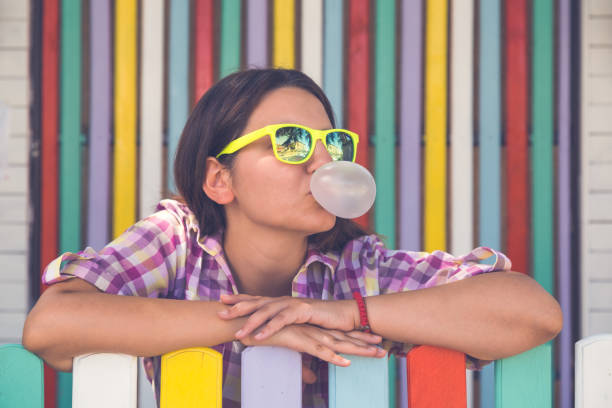 Young female leaning on fence and chewing gum