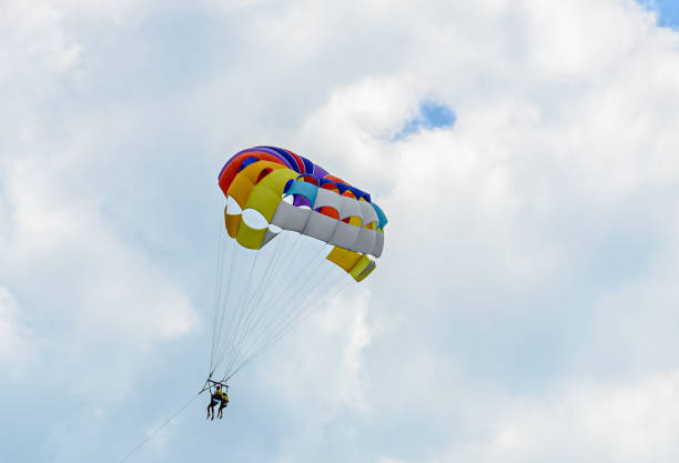 istock Colored parasail wing in the blue clouds sky, Parasailing also known as parascending or parakiting 830374238