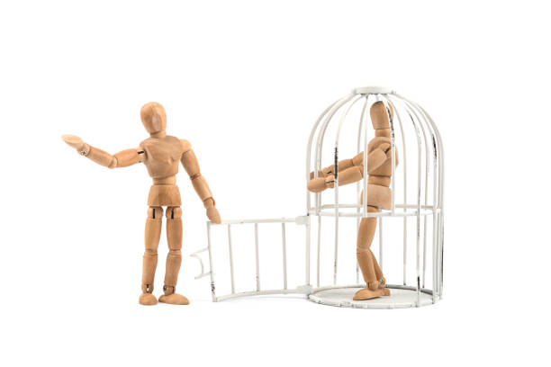 istock Wooden mannequin in cage / trap or prison with help 830385544