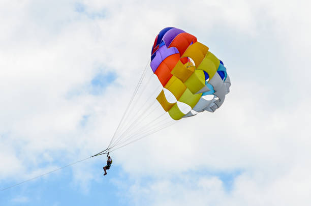 istock Colored parasail wing in the blue clouds sky, Parasailing also known as parascending or parakiting 830405712
