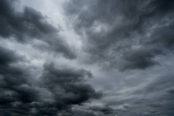 istock clouds with background,sunlight through very dark clouds background of dark storm clouds, black sky Background of dark clouds before a thunder. 830406160
