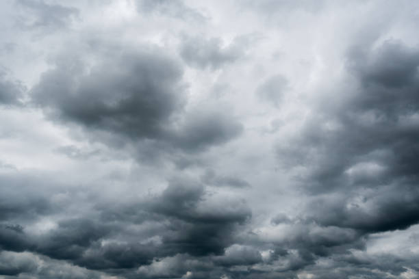 istock clouds with background,sunlight through very dark clouds background of dark storm clouds, black sky Background of dark clouds before a thunder. 830406276