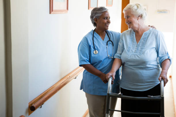 istock Nurse assisting patient in walking with walker at retirement home 830421162