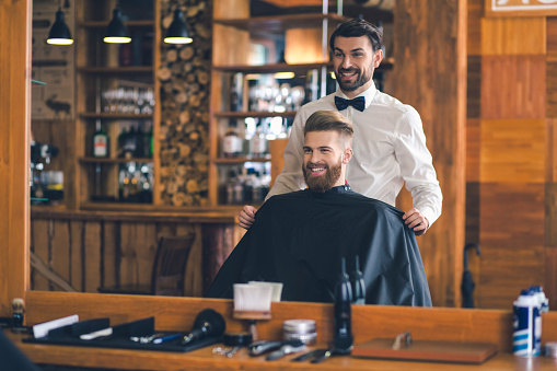 Young man sitting in a barbershop cheerful preparation for the haircut