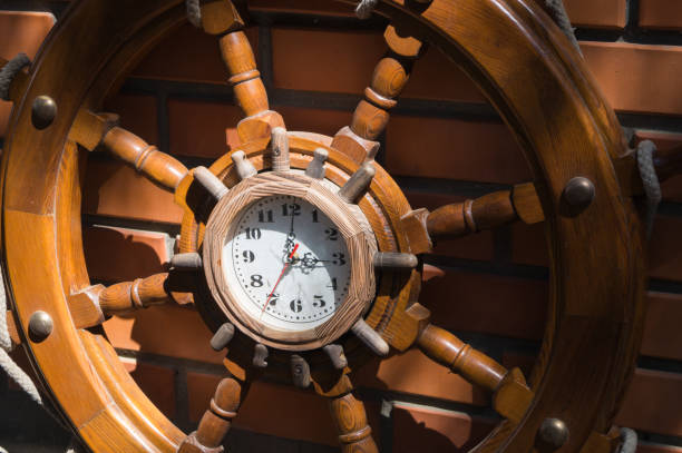 volante decorativo in legno della nave con un orologio sul muro di mattoni - noontime foto e immagini stock