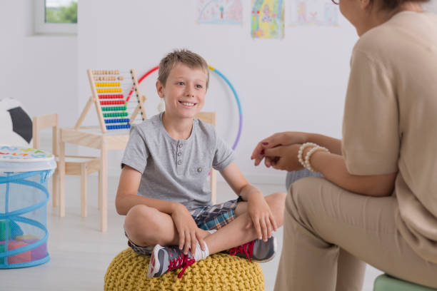 jeune garçon assis sur un pouf jaune en salle de classe - rackets and ball photos et images de collection