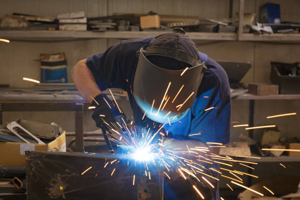 istock Male in face mask welds with argon-arc welding 830457942