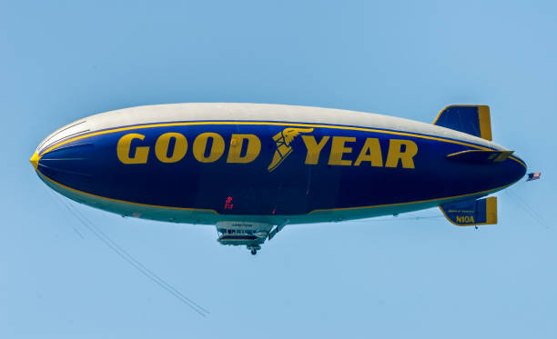 Famous Goodyear blimp, which has become an icon representing American automotive industry, delights beach goers by flying over California coastline during summer season. The picture was taken from Malibu beach in Southern California, when thousands of tourists and locals take to the beach.