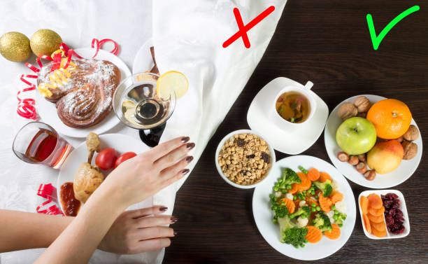 Table with healthy and unhealthy food and alcohol. Woman hands covering the part with harmful dishes and drinks with table cloth. stock photo