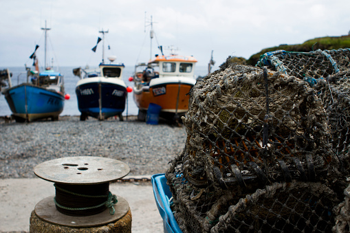 lobster pot with fishing boats in the background on a Cornish beach.