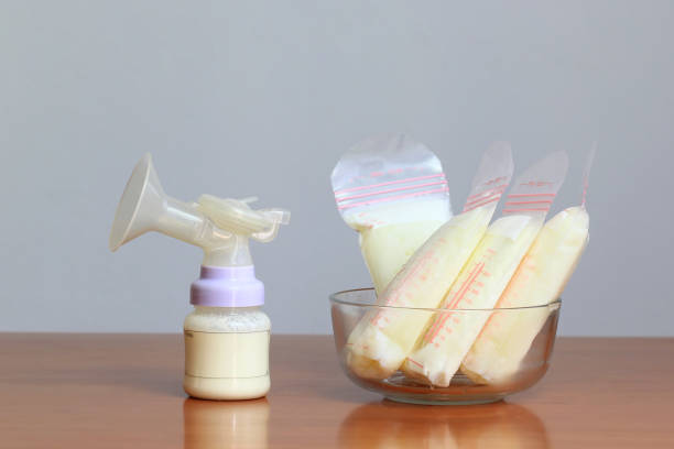 botellas y bolsas de almacenamiento de leche materna congelada para bebé nuevo en la mesa de madera - human nipple fotos fotografías e imágenes de stock