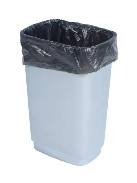 Photo of Empty trash container with black plastic bag on white background