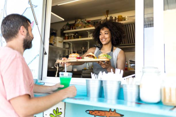 istock Smiling food van worker offering sandwiches 830593526