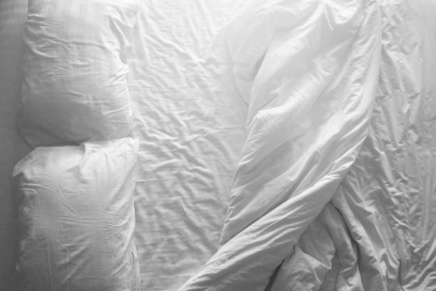 istock Messy double bed. Two pillows and blanket on white cover sheets. Top view. Black and white theme. 830621636