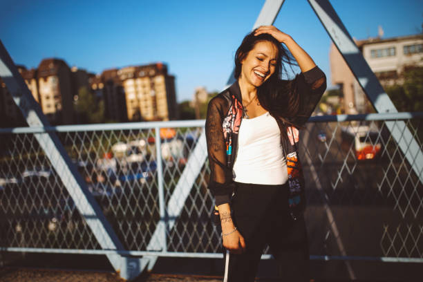 Vintage toned portrait of a young fashionable brunette walking downtown and enjoying the warm summertime day, wearing sunglasses and a vintage tracksuit.