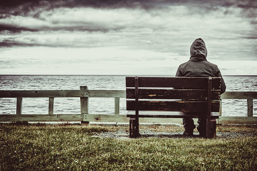 Hombre sentado sobre un banco con vistas al mar photo