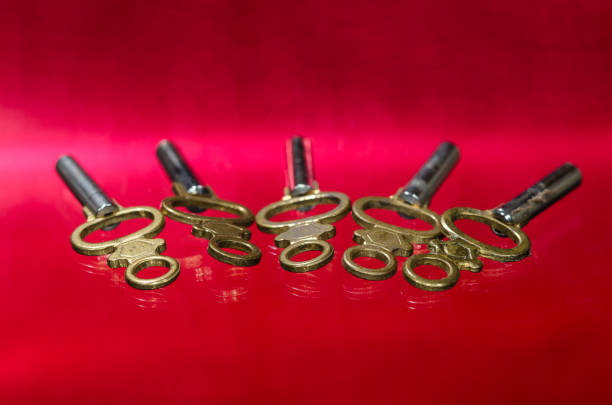 Cinque antiche chiavi dell'orologio da tasca in ottone posate su superficie rossa - foto stock