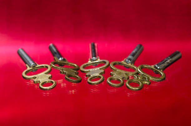 Five Antique Brass Pocket Watch Keys Laying on Red Surface