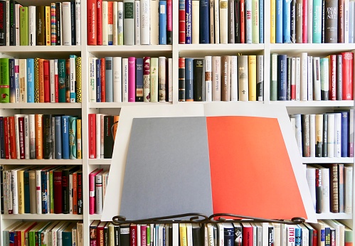 Music stand with open grey orange sheets in front of book shelves