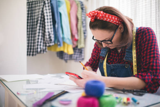 istock Young fashion designer talking on cellphone, watching her designs 830727190